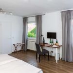 Hotel room with double bed, chair, table, and TV